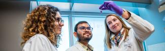 Researchers in lab looking at a vial